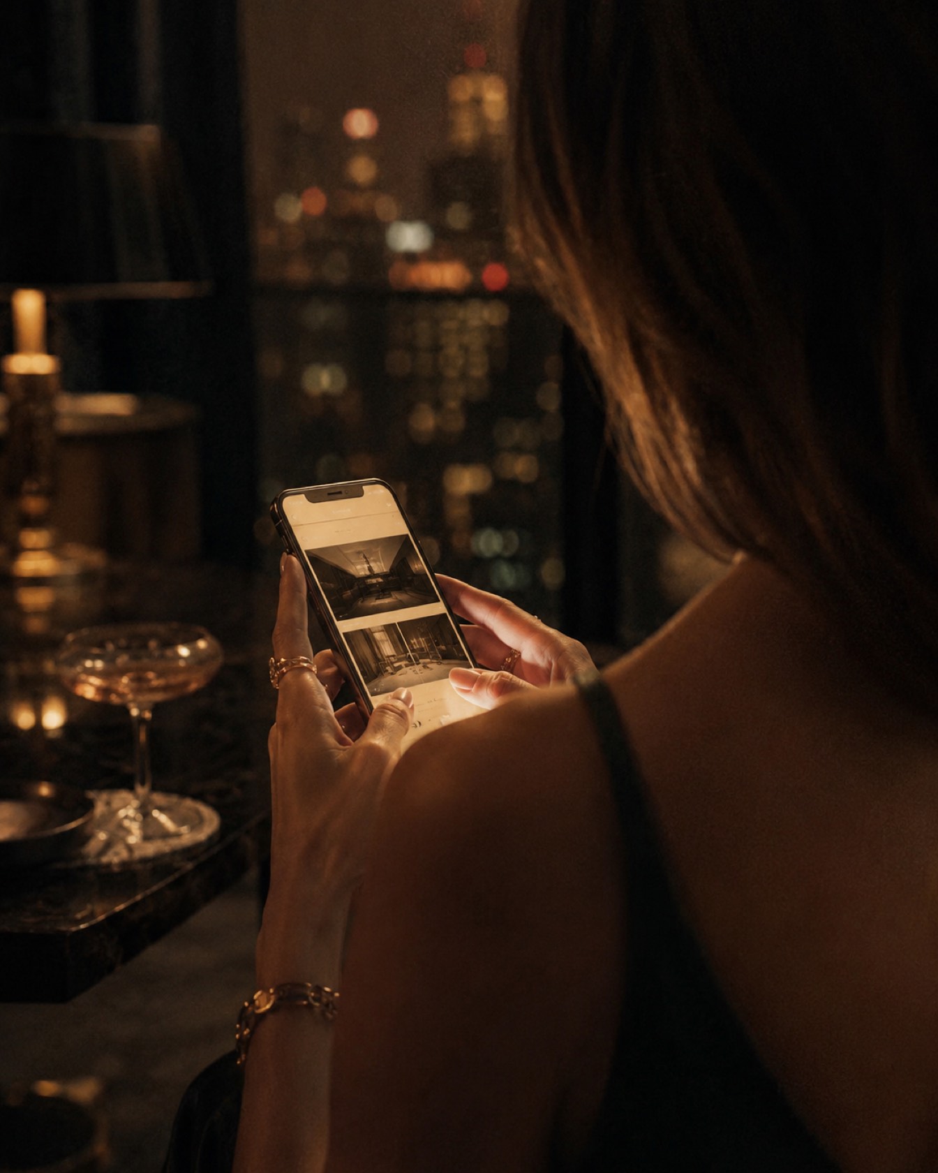 Silhueta de uma mulher com o celular e as luzes da cidade desfocadas ao fundo